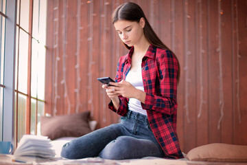A teen girl looking at her cell phone with a serious look.