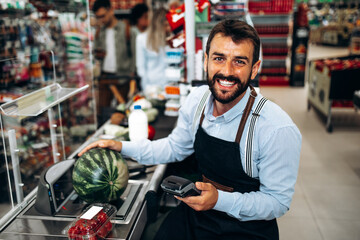 Portrait of handsome smiling male cashier working at a grocery store.