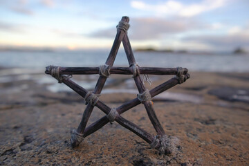 Pentagram made of small wood sticks. Beach and sea horizon in the background. Esoteric and Occult...