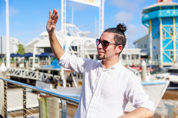 海の近くで手を挙げて挨拶をするヒスパニック系の男性