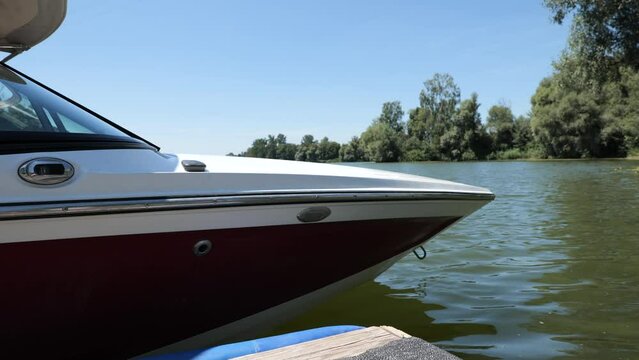 Wide angle shot of a ski boat docked at the pier on a lake. A relaxing, calm, empty scene with no people. 