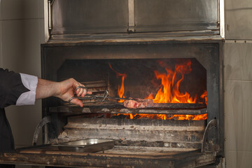 Chef makes beef steak on open fire in restaurant