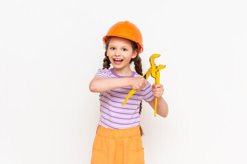 Renovation in the children's room. A child in a construction helmet and a monkey wrench on a white isolated background. Work as a builder, choosing a profession for a child.