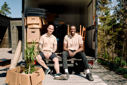 Delivery company employees smiling while sitting in truck on sunny day