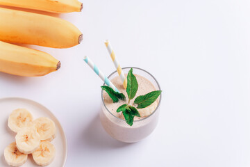 Obraz na płótnie Canvas Banana smoothie with ingredients on white background. Top view, flat lay