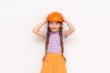 A child in a construction helmet holds his head with his hands. A beautiful little girl is getting ready for repairs on a white isolated background.