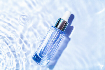 Glass serum bottle with collagen on blue water background with water bubbles. Advertising of...
