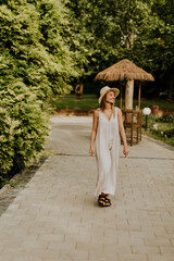 Fototapeta na wymiar Young woman with hat walking in the resort garden
