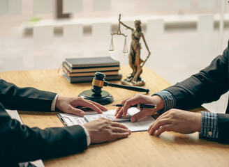 Fototapeta premium A meeting of professional business women and male lawyers working and discussing at the judge's hammered office with the scales of justice laid alongside the concept of law and consulting services.