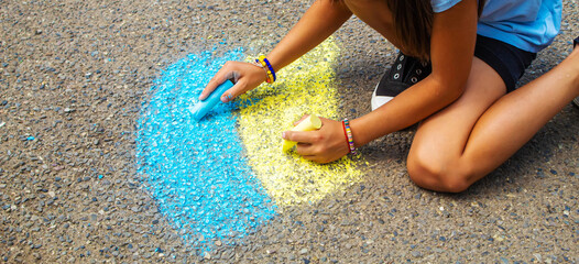 Children draw the Ukrainian flag house on the pavement. Selective focus.