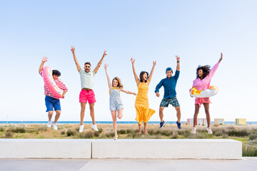 Obraz premium Group of young best friends bonding outdoors - Multiracial people bonding and having fun at the beach during summer vacation