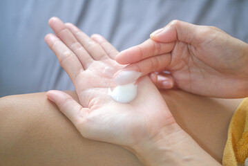 Naklejka premium Asia woman sitting on bed and applying cream on her hand.