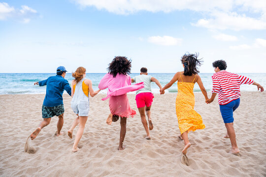 Group of young best friends bonding outdoors - Multiracial people bonding and having fun at the beach during summer vacation