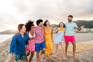 Group of young best friends bonding outdoors - Multiracial people bonding and having fun at the beach during summer vacation