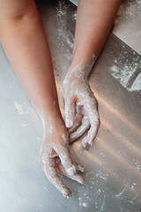 Fototapeta premium baker's hands in flour on the metallic table