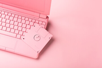 Colored pink laptop with bright floppy disk, modernity concept.