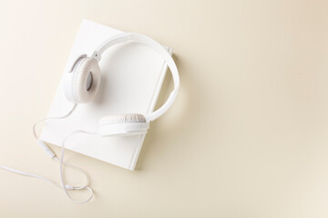 Top view of white headphones and notebooks on background with copy space. Flat lay.