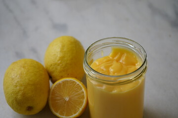 Fototapeta na wymiar Lemon curd, and lemon custard in a glass bottle on a white marble table