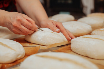 baker shaping bread raw dough before baking on the table in bakery