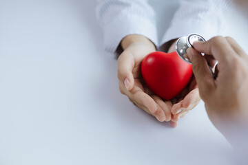 A doctor uses a stethoscope with a fake heart in the patient's hand, treating the disease from a medical professional and giving treatment on the spot. Concepts of medical treatment and specialists.