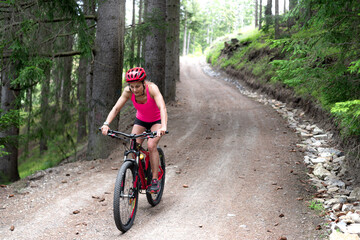 the sportswoman rides on a mountain hardtail bike on the forest road.