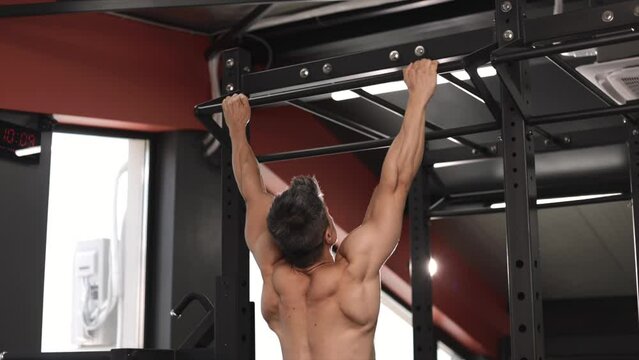 Middle age man pumping up muscle doing pull-ups exercises in gym naked torso. Handsome strong athletic men pumping up back muscles workout fitness and bodybuilding concept background
