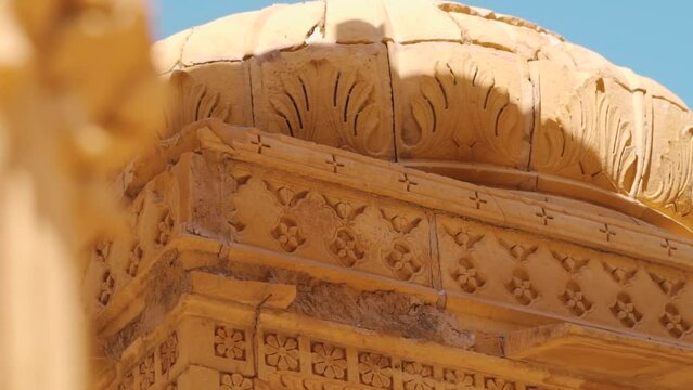 Closeup shot of carvings on the top portion of the chattri dome cenotaph at Bada Bagh in Jaisalmer, Rajasthan, India. Carvings on top of the structure made out of sandstone. Ancient carving on dome. 