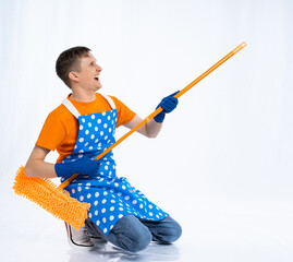 a man in a blue apron, rubber gloves, an orange t-shirt, jeans and white sneakers plays a mop like...