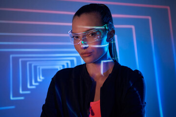 Beautiful young woman in futuristic glasses looking at camera