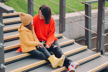 Image of fashionable young woman wears red looe sweater, looks positively at small child, pose...