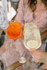 Aperol cocktail in glass. Women drinking summer cocktails while resting in cafe together.