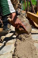 Worker building wall with ladle mortar