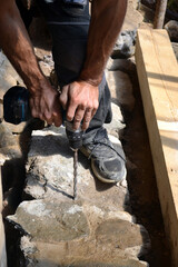Worker of construction drilling  stone with a power drill. Making a hole in the foundation of a house using a perforator with a long drill