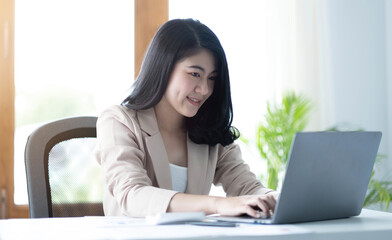 Beautiful young asian woman sitting at coffee shop using laptop. Happy young businesswoman sitting at table in cafe with tab top computer.