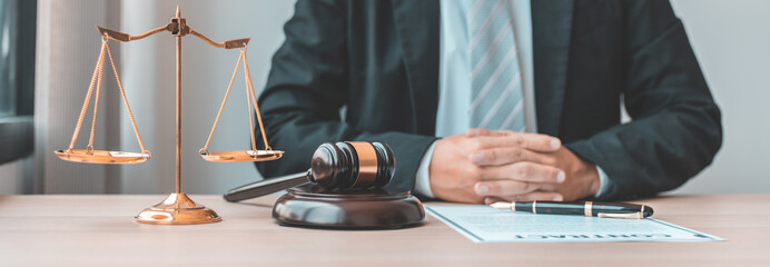 Male lawyer or judge sits and analyzes the case and decides the case with fairness, On the table were the scales of justice and the hammer of honest judgment, Concepts of Law and Legal services.