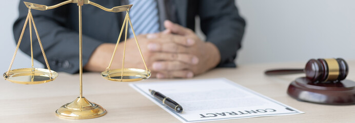 Male lawyer or judge sits and analyzes the case and decides the case with fairness, On the table were the scales of justice and the hammer of honest judgment, Concepts of Law and Legal services.