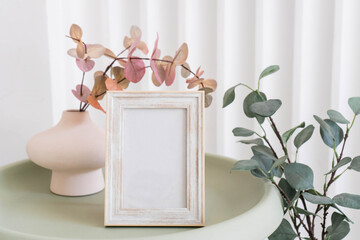 Portrait white picture frame mockup on table. Modern ceramic vase. Scandinavian interior. 