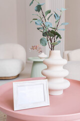 Portrait white picture frame mockup on table. Modern ceramic vase. Scandinavian interior. 