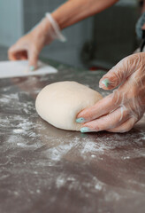 baker shaping bread raw dough before baking on the table in bakery