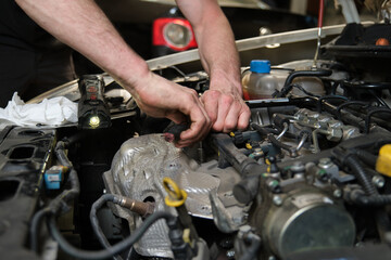 Close up of car mechanic hands doing car service and maintenance. Mechanics workshop.