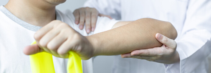Physical therapy, Female physiotherapist uses an elastic band to test the arm injury of a male...