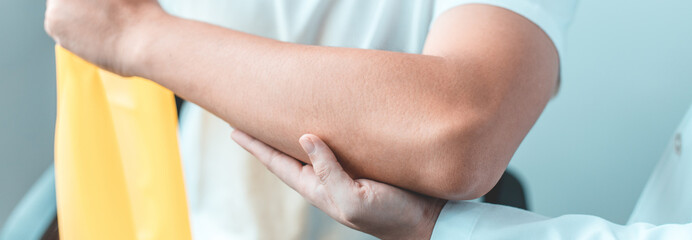 Physical therapy, Female physiotherapist uses an elastic band to test the arm injury of a male patient attending in clinic, Bone arrangement, Non-surgical medical treatment, Medical techniques.
