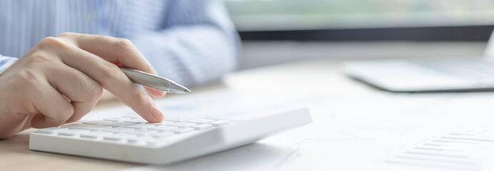 Young Asian businesswoman presses a calculator to calculate income tax and corporate income in a private office, Finance, Accounting, Tex, Statistical graphs of marketers investing in real estate.