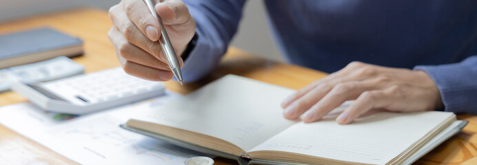 Men are taking notes on household income and expenses and working to save money for future use, Money management for use when needed, Saving money for future growth and knowing how to manage money.