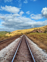 Fototapeta na wymiar Railway train track , blue sky, clouds and mountains at Itabira Minas Gerais, Brazil