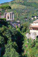 View to the ancient buildings in the a picturesque valley surrounded by green trees and bushes in sunny summer day with mountain in background