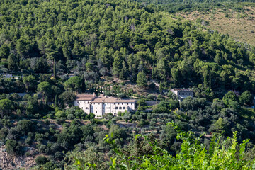 View from the top of mountain to the ancient building in the a picturesque valley surrounded by distinctly green trees and bushes in sunny summer day