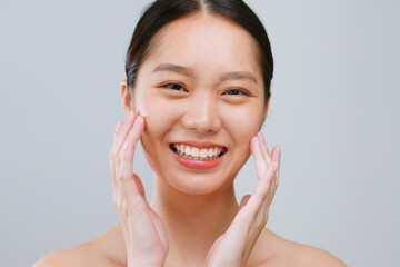 Portrait young Asian woman touching healthy facial beauty skin over grey background.