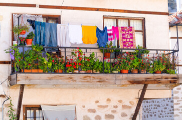 Flowers on the balcony of an old house and clothes hanging on a wire