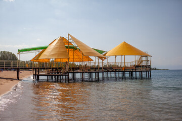 Swimming area or pier on the sea. A large pier with a roof, wooden planks and rusty stairs descending into the water. Bathing and resting place.